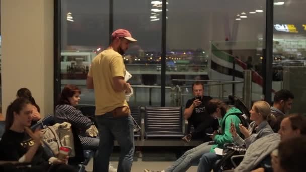 Dubai, Emirados Árabes Unidos - 19 de novembro de 2019: Um grupo de pessoas esperando em um lounge em um terminal à noite. Sala de espera do aeroporto. Uma pessoa à procura de alguém . — Vídeo de Stock