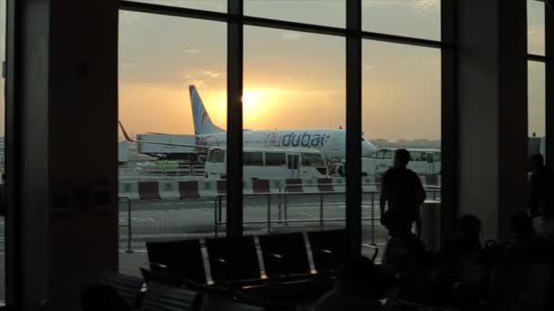 Dubai, VAE - 19. November 2019: Eine Person betrachtet am Flughafen-Terminal ein Flugzeug. Dubai Airline. Sonnenuntergang, Sonnenaufgang. — Stockvideo