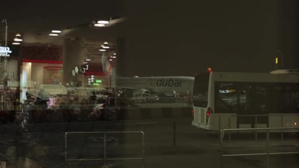 Dubaj, SAE - 19. listopadu 2019: Pohled na letištní terminál, noční přestup přes skleněné okno na letišti. Letadlo a autobus. — Stock video