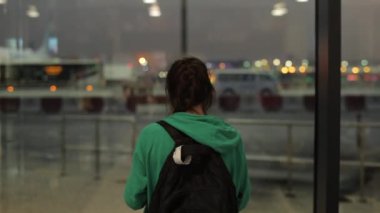 Genç bir kız, bir kadın gece havaalanında bekleyen ve fotoğraf çeken bir kadın. Arka arkaplan.