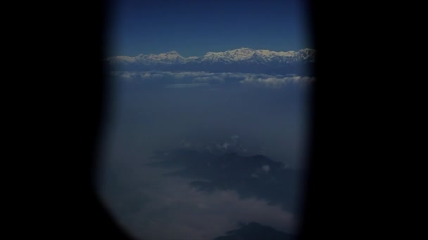 Ein Blick aus einem Flugzeugfenster auf Schneeberge und Wolken. — Stockvideo