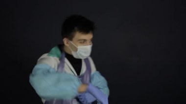 Tıbbi kıyafet giyen ve maske takan çılgın bir doktor. İzole edilmiş siyah arka plan. Mutluyum. Koronavirüs. covid-19