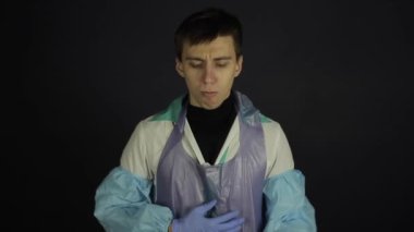 Korunaklı tıbbi kıyafetli genç bir adam Coronavirus modeli öksürüyor, örnek olarak. İzole edilmiş siyah arka plan. Şaşırdım. Çizim
