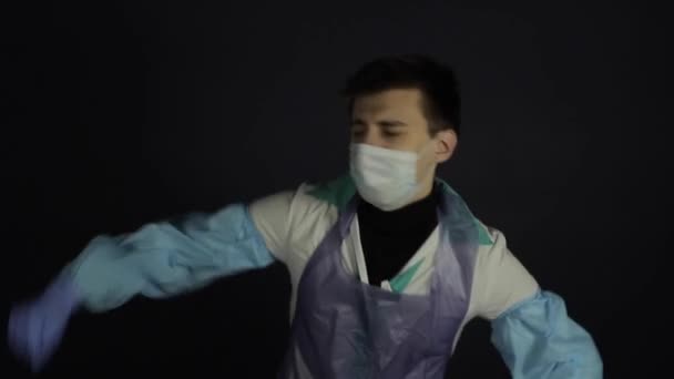Verrückter Arzt in medizinischem Anzug und Maske beim Tanz. Vereinzelt schwarzer, dunkler Hintergrund. Glücklich. — Stockvideo