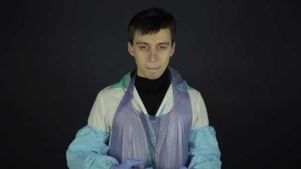 En ung kaukasisk man som hostar ut en coronavirus modell, prov. Isolerad svart mörk bakgrund. Förvånad och förvirrad. Skiss — Stockvideo