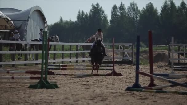 Минск, Беларусь - 19 июля 2019 года: Лошадь с молодой девушкой-жокеем в седле перепрыгивает через барьеры в соревнованиях — стоковое видео