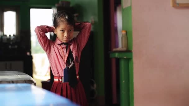 Kathmandu, Nepál - 2019. november 14.: Egy kis nepalese lány stílus, fonás, fésülködés iskola előtt. Iskolai egyenruha. Napsütés. — Stock videók