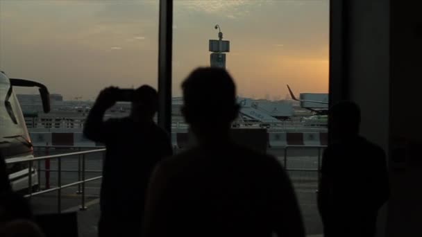 Dubaj, SAE - 19. listopadu 2019: Osoba hledící na letadlo na letištním terminálu. Dubajské aerolinie. Západ slunce, východ slunce. — Stock video