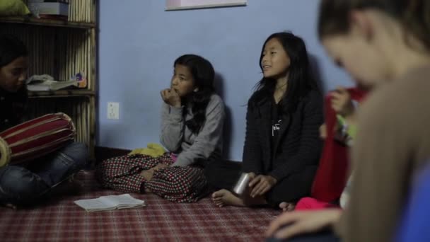 Kathmandu, Nepal - 14 November 2019: Beautiful Asian Nepalese Indian girls sitting in a circle on the floor singing, clapping and smiling. Casual warm clothes. Poverty. — стокове відео