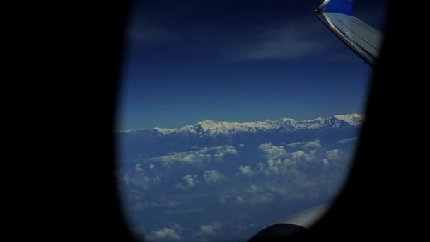 Una vista forma una finestra di aeroplano sulle montagne di neve e le nuvole . — Video Stock