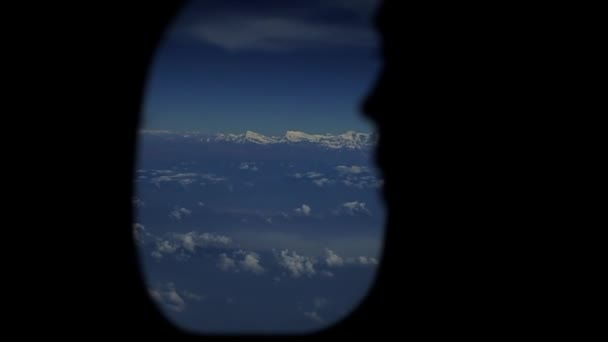 Uma visão próxima de uma silhueta de pessoas que olha para fora da janela de aviões. Vista do céu e nuvens de uma janela de avião . — Vídeo de Stock