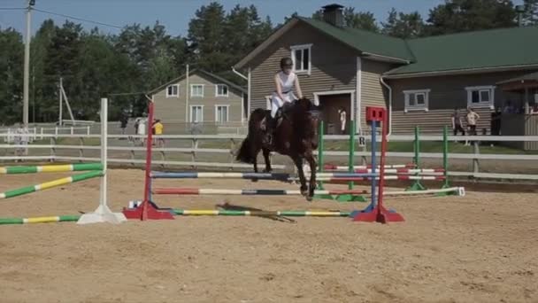ミンスク、ベラルーシ- 19 7月2019:女の子のジョッキーは馬術競技で障壁を飛び越えながら馬を運転します。スローモーション — ストック動画
