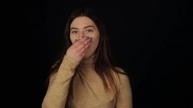 Genç beyaz bir kız öksürüyor ve kameraya bakıyor. İzole edilmiş siyah arka plan. Coronavirus COVID19