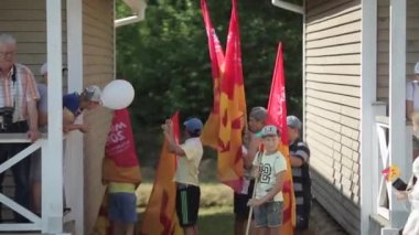 Minsk, Belarus - 19 Temmuz 2019: Bayraklı gençler ormanın arka planındaki evlerin yakınındaki bir grupta duruyorlar.