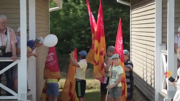 Minsk, Belarus - 19 juli 2019: Tienerjongens met vlaggen staan in een groep bij huizen op de achtergrond van het bos. — Stockvideo