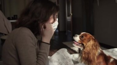 Güzel Avrupalı kız köpeğini tıbbi bir maskeyle öpüyor. Coronavirüs. COVID-19.