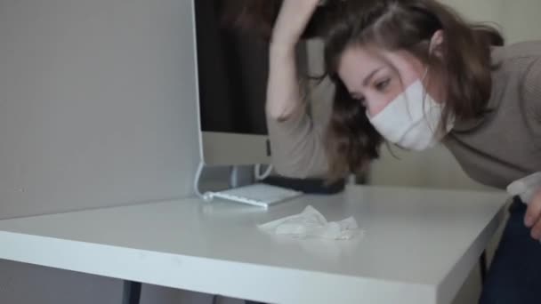 Una giovane donna mascherata protettiva in quarantena alleva una disinfezione desktop a casa. Coronavirus COVID-19 — Video Stock