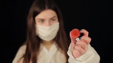 Coronavirus COVID-19 modeline bakan koruyucu giysili ve tıbbi maskeli beyaz bir kız. Koyu arkaplan.