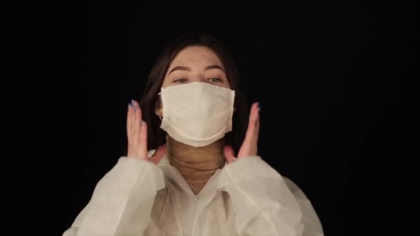 Καυκάσια κοπέλα που φοράει ιατρική μάσκα και λευκό κοστούμι ενάντια στον πανδημικό κορωναϊό. — Αρχείο Βίντεο