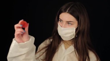 Coronavirus COVID-19 modeline bakan koruyucu giysili ve tıbbi maskeli beyaz bir kız. Koyu arkaplan.