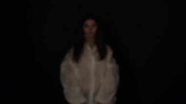 Genç beyaz kız karanlıkta beliriyor ve kırmızı maske solunum cihazını takıyor. Coronavirus COVID-19