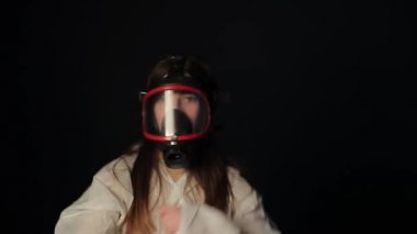 Tıbbi koruyucu takım elbiseli, maske takmış, dans eden ve eğlenen neşeli genç kız.