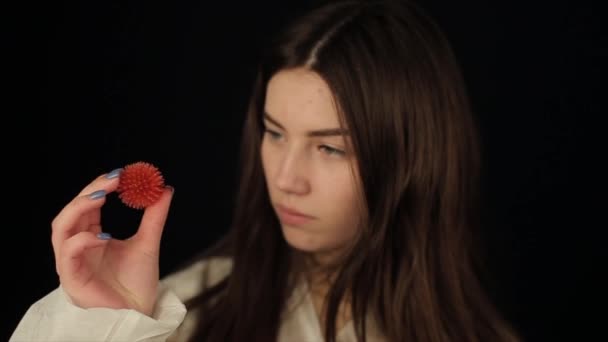 Flicka i skyddskläder tittar på en Coronavirus COVID-19 modell. Mörk bakgrund. — Stockvideo