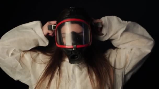 Ung flicka sätta på sig full ansikte respirarory mask och titta på coronavirus mini modell. COVID-19 — Stockvideo