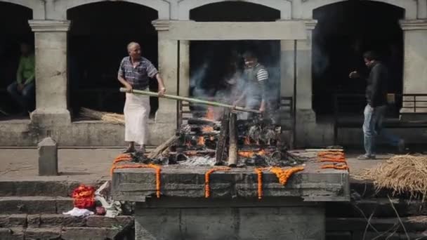 Kathmandu, Nepal - 14. November 2019: Ein Mann schaufelt eine brennende Leiche in Kathmandu, Nepal. Feuerbestattung. — Stockvideo