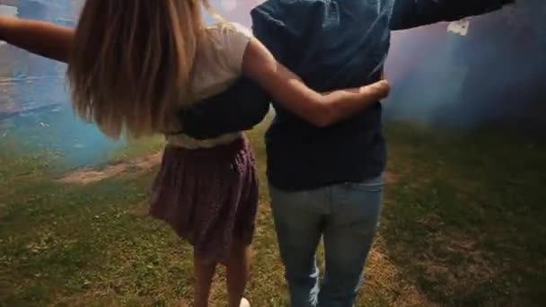 Um jovem casal feliz a girar com bombas de fumo nas mãos. Vista próxima. Movimento lento — Vídeo de Stock