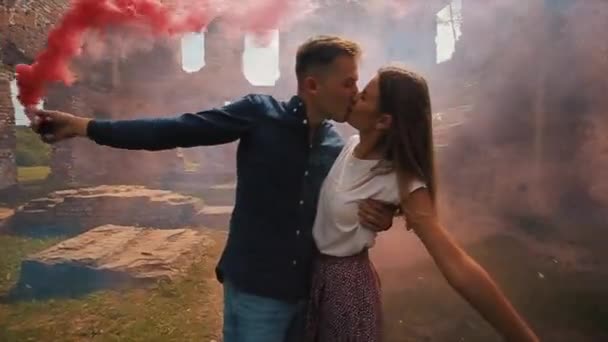 Vista de perto de um jovem lindo casal beijando segurando bombas de fumaça em suas mãos — Vídeo de Stock