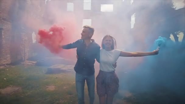 Joyeux jeune couple marchent ensemble avec des bombes fumigènes dans leurs mains. Vue rapprochée. Mouvement lent — Video