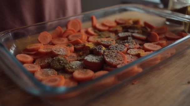 Нарезанная морковь в стеклянной чаше и посыпанная большим количеством специй и соли. Крупный план — стоковое видео
