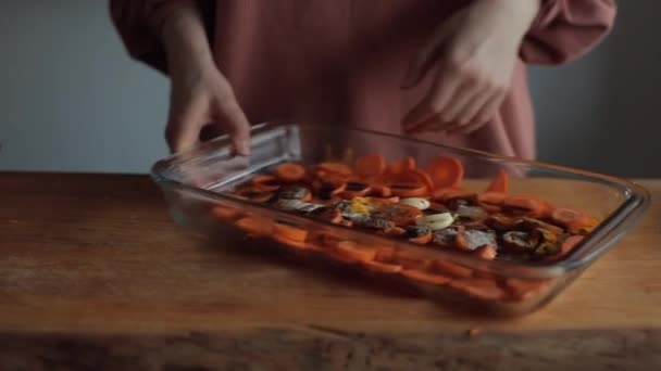 Uma menina nas mãos da cozinha mistura cenouras picadas com especiarias e molho em uma tigela de vidro grande. Close-up — Vídeo de Stock