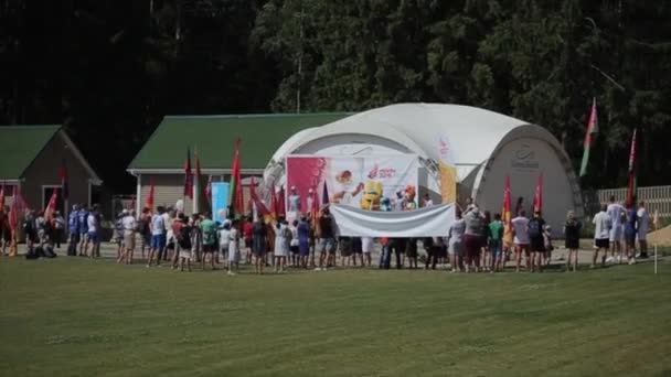Minsk, Bielorrússia - 19 de julho de 2019: Na abertura dos 2 Jogos Europeus, um grupo de pessoas está com bandeiras no gramado da cena da frente com atletas realizando — Vídeo de Stock