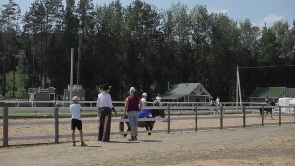 Minsk, Bielorussia - 19 luglio 2019: Vacanze estive con famiglie e passeggiate a cavallo in un ranch in un recinto sullo sfondo della foresta — Video Stock