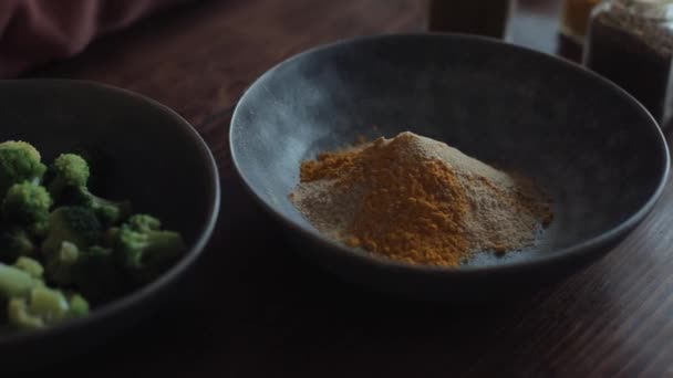 Op de keukentafel staan kommen met een mengsel van specerijen en broccoli voor het bereiden van gezond voedsel. Close-up — Stockvideo