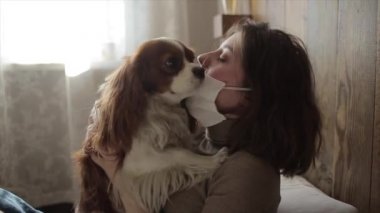 Güzel Avrupalı kız köpeğini tıbbi bir maskeyle öpüyor. Coronavirüs. COVID-19.