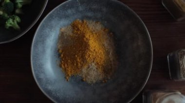 Kız mutfağında yemek pişirmek için bir kasede çeşitli baharatlar karıştırıyor. Yakın plan. Yukarıdan görüntüle