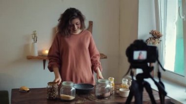 Güzel gülümseyen kız yemek blogu için mutfaktaki dairesinde yemek pişirmekten bahsediyor. Kadın yemek blogcusu