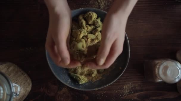 Bir kızın elleri brokoliyi sağlıklı yemek pişirmek için baharatlarla karıştırırken ağır çekimde. Yakın plan. — Stok video