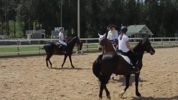 Minsk, Bielorrússia - 19 de julho de 2019: Jovens meninas bonitas em um traje de cowboy e um belo vestido montam cavalos em um curral em um rancho — Vídeo de Stock