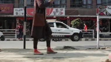 Katmandu, Nepal - 23 Kasım 2019: Nepal kaldırımı ve bir yol manzarası. Bir kadın, bacakları geçiyor. Araba kullanan insanlar.