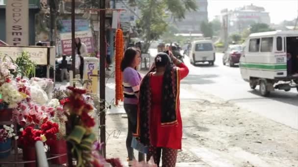 Kathmandu, Nepal - 23. November 2019: Nepalesinnen in traditioneller Kleidung unterhalten sich auf einem Bürgersteig. Belebte nepalesische Straße im Hintergrund. — Stockvideo