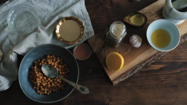 Sada ingrediencí na dřevěném stole pro domácí vaření tradičního hummusu. Pohled shora — Stock video