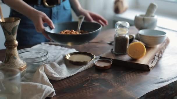 Großaufnahme weiblicher Hände, die Kichererbsen in einer Schüssel rühren, um hausgemachten Hummus auf dem Küchentisch zu kochen — Stockvideo