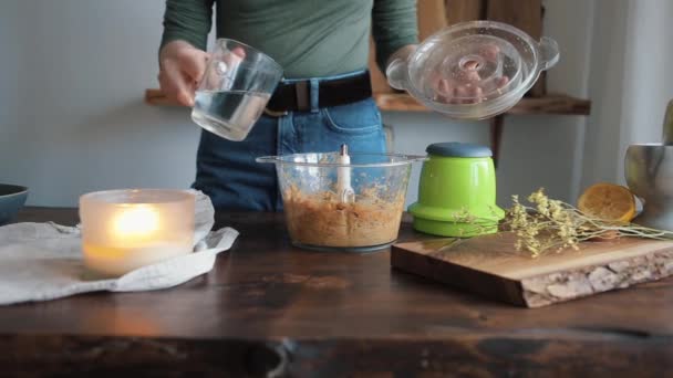 Genç bir kız miksere su eklemiş ve ev yapımı humus yapmak için içindeki tüm malzemeleri karıştırmış. Yakın plan. — Stok video