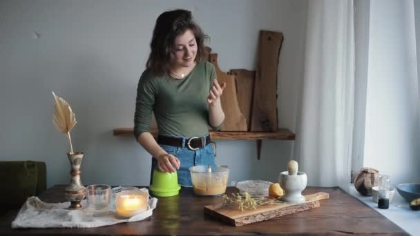 Jong mooi meisje in haar keuken smaakt de hummus gekookt door haar van een blender en lacht — Stockvideo