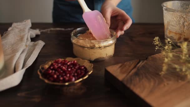 Een meisje met behulp van een keuken siliconen spatel plat koken gezonde zelfgemaakte hummus in een glazen kom. Close-up — Stockvideo