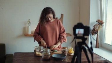 Genç bir blogcu kız kameranın önünde yemek pişirmekten ve aynı zamanda salatalık yemekten bahsediyor.